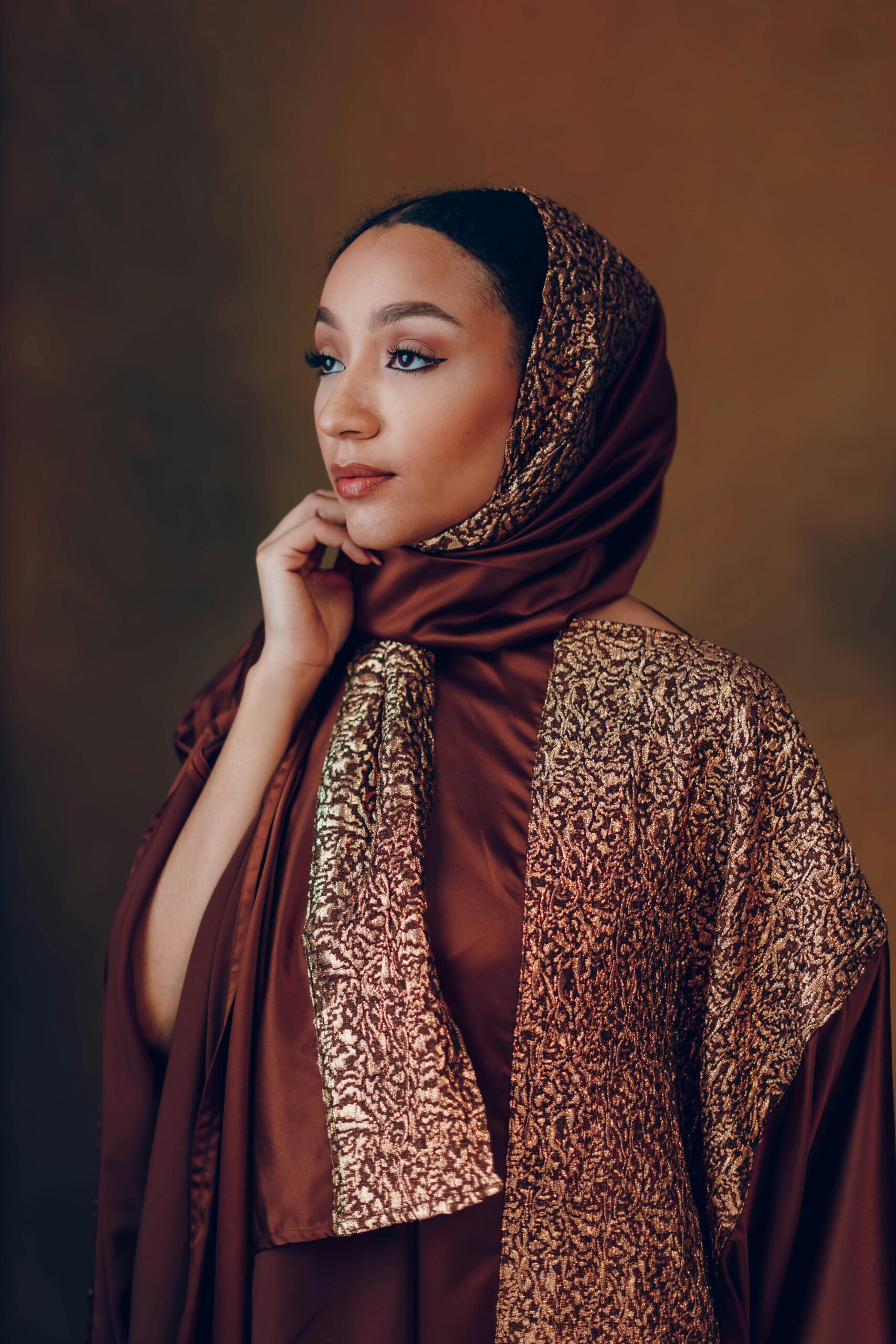 Portrait of a thoughtful woman in ornate brown traditional dress.